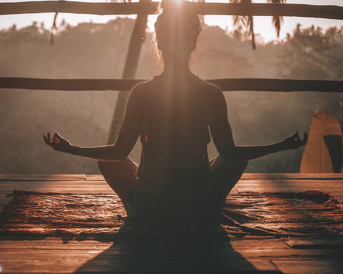 A woman at sunrise, seen from behind, taking a quiet moment