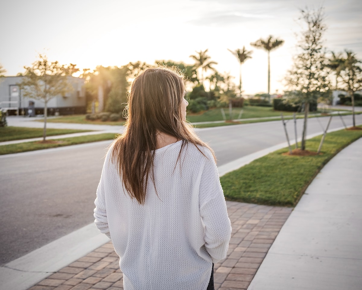 Maya walking her street in the late afternoon, seen from behind