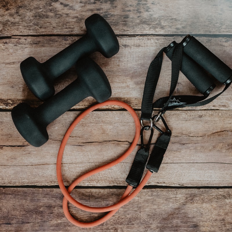 Dumbbells and a resistance band on a wooden floor — the two-session minimum